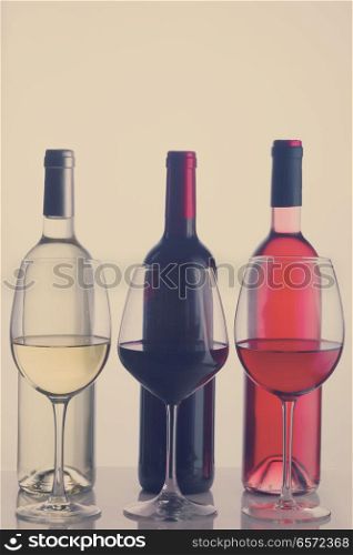 Set of three wine glasses and bottles with red, white and rose wine, retro toned. Set of glasses with wine