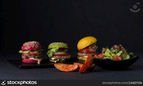 set of variated color cheeseburgers on a flat plate on a black background. fast food on a black background