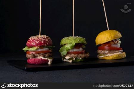 set of variated color cheeseburgers on a flat plate on a black background. fast food on a black background