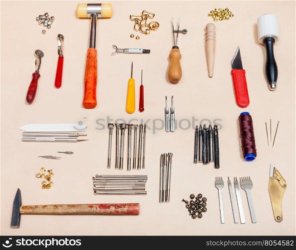 set of various leathercraft tools on natural leather surface