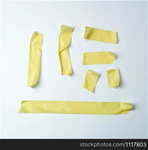 set of various pieces of yellow sticky paper tape on a white background, close up