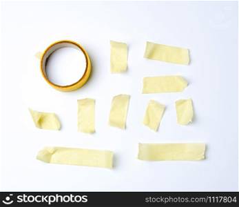 set of various pieces of yellow sticky paper tape on a white background, close up