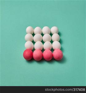 Set of white and pink colored eggs in the form of a square on a green background with copy space for text. Creative layout for your ideas. Billiard balls concept. Beautiful Easter composition made of painted pink and white eggs on a green background with copy space. Billiard game concept.