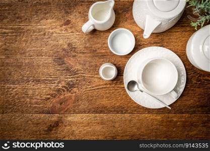 Set of white empty dishes or tableware on wooden background, top view. Set of white empty dishes