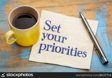 Set your priorities reminder - handwriting on a napkin with a cup of espresso coffee