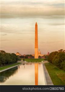 Setting sun illuminates Washington Monument in DC and Capitol with reflections in new Reflecting Pool