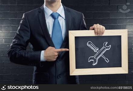 Settings and tools. Close up of businessman holding wooden frame with tools concept