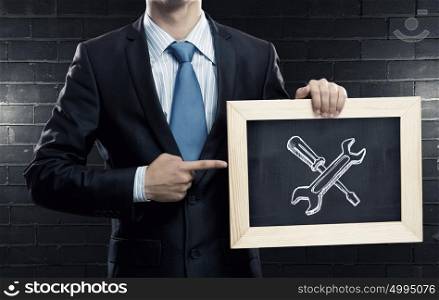 Settings and tools. Close up of businessman holding wooden frame with tools concept