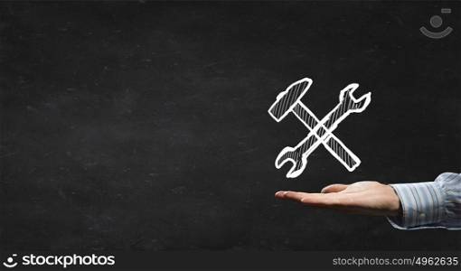 Settings icon. Businessman&rsquo;s hand holding tools over gray background