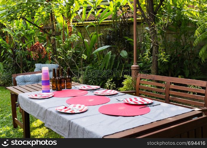 settle wooden table outdoor and red plate with beers for food and prepare for barbecue camping party together in nature
