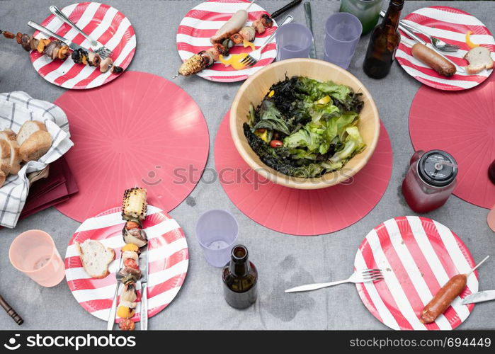 settle wooden table outdoor and red plate with beers for food and barbecue after camping party, top view