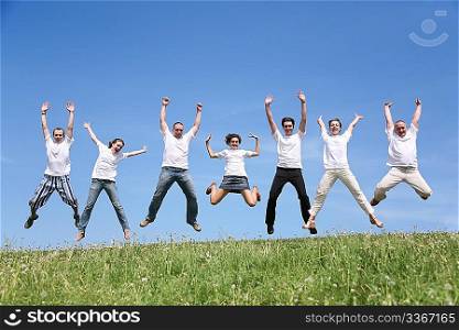 Seven friends in white T-shorts joyfully jump together