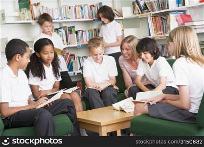 Seven students in library reading books with teacher
