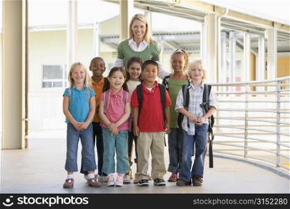 Seven students standing with teacher outdoors at school