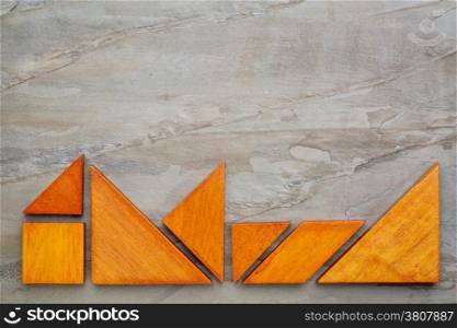 seven tangram wooden pieces, a traditional Chinese puzzle game, on a slate rock background with a copy space