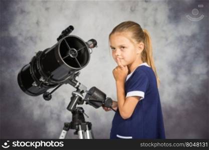 Seven-year girl looks at the sky while standing at the telescope
