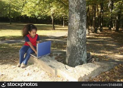 Seven year old child outside with laptop computer.