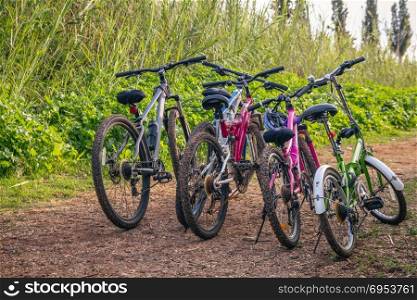 Several bicycles parked on a dirt road.
