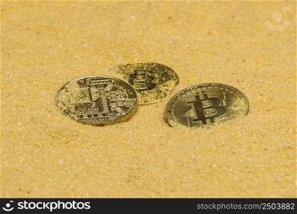 several bitcoin crypto coins on brilliant golden sand. finding and mining cryptocurrency. bitcoin on golden sand