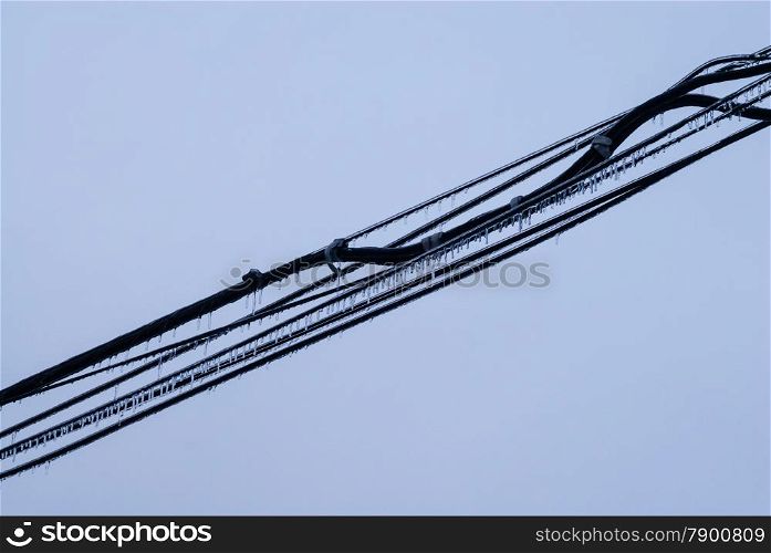 Several black cables covered in ice across empty gray background.