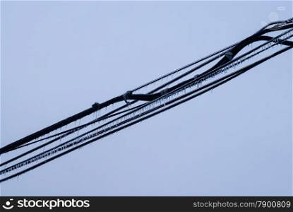 Several black cables covered in ice across empty gray background.