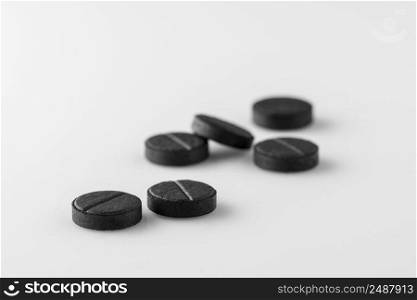 several black medical activated charcoal pills on white background. Isolated. tablets on a light surface