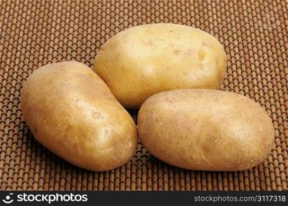 Several brown potatoes lies on a mat