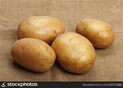 Several brown potatoes lies on a sacking