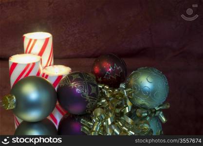 several Christmas ornaments by candlelight with reflections