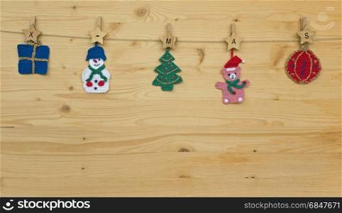 Several crocheted christmas hangers on a cord on wood and text x-mas, background