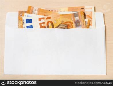 several fifty euro notes in open mail envelope on wooden table