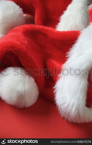 Several furry Santa Claus hats on a red background with copy space