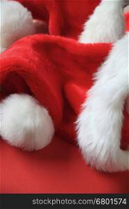 Several furry Santa Claus hats on a red background with copy space