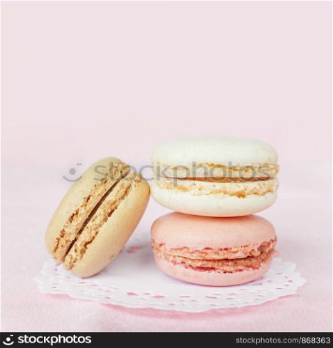 Several multicolored macaroons pastel colors on pink background