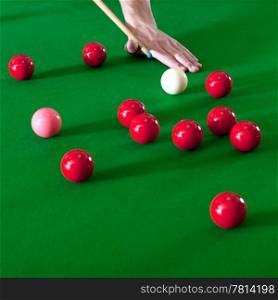 Several red snooker balls and the pink ball on a snooker table-