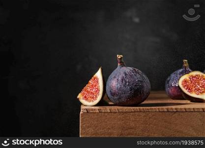 Several ripe figs on a wooden box in raindrops. Close-up, selective focus