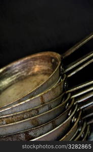 Several stacked frying pans in commercial kitchen.