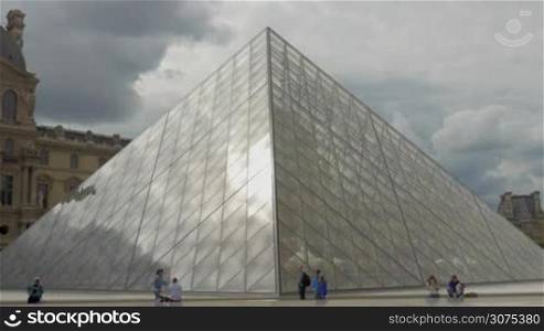 Several tourists by the Louvre Pyramid. It is the main entrance to the Louvre Museum and popular landmark of Paris