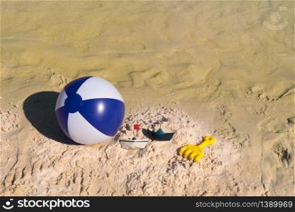 Several toys as ball and paper boat at the beach