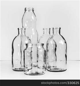Several transparent empty glass bottles and jars. Black and white vintage blurred background with space for copy. Selective focus.
