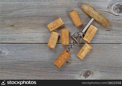 Several used wine corks and opener on rustic wooden boards. Top view angled shot in horizontal format with copy space.