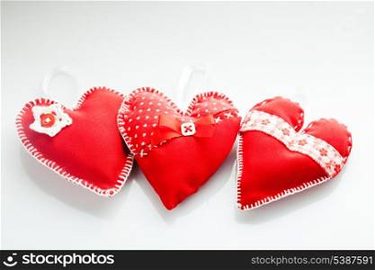 Sewed handmade red hearts on a white background