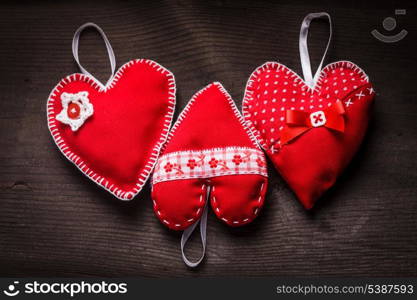 Sewed handmade red hearts on wooden background