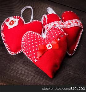 Sewed handmade red hearts on wooden background