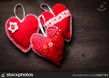 Sewed handmade red hearts on wooden background. Handmade red hearts