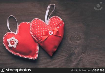 Sewed two handmade red hearts on wooden background