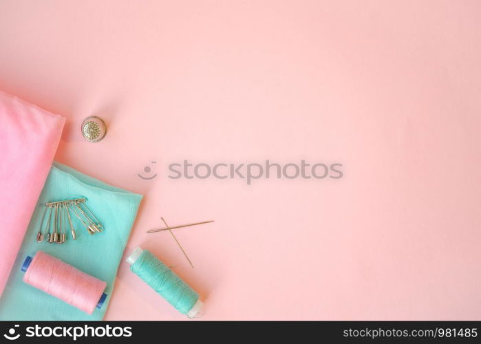 Sewing accessories, turquoise and pink fabric on pink background. Fabric, pins, threads and needles. Copyspace. Sewing accessories, turquoise and pink fabric on pink background. Fabric, pins, threads and needles.