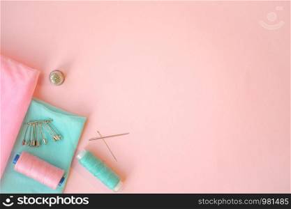 Sewing accessories, turquoise and pink fabric on pink background. Fabric, pins, threads and needles. Copyspace. Sewing accessories, turquoise and pink fabric on pink background. Fabric, pins, threads and needles.