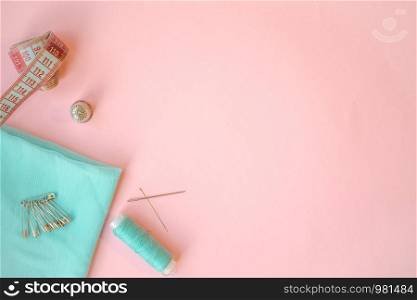Sewing accessories, turquoise fabric on pink background. Fabric, pins, threads and needles. Copyspace. Sewing accessories, turquoise fabric on pink background. Fabric, pins, threads and needles.