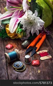 sewing accessories with a bouquet of fresh flowers.the image is tinted in vintage style